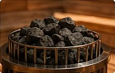 Dark sauna stones in a steel basket.